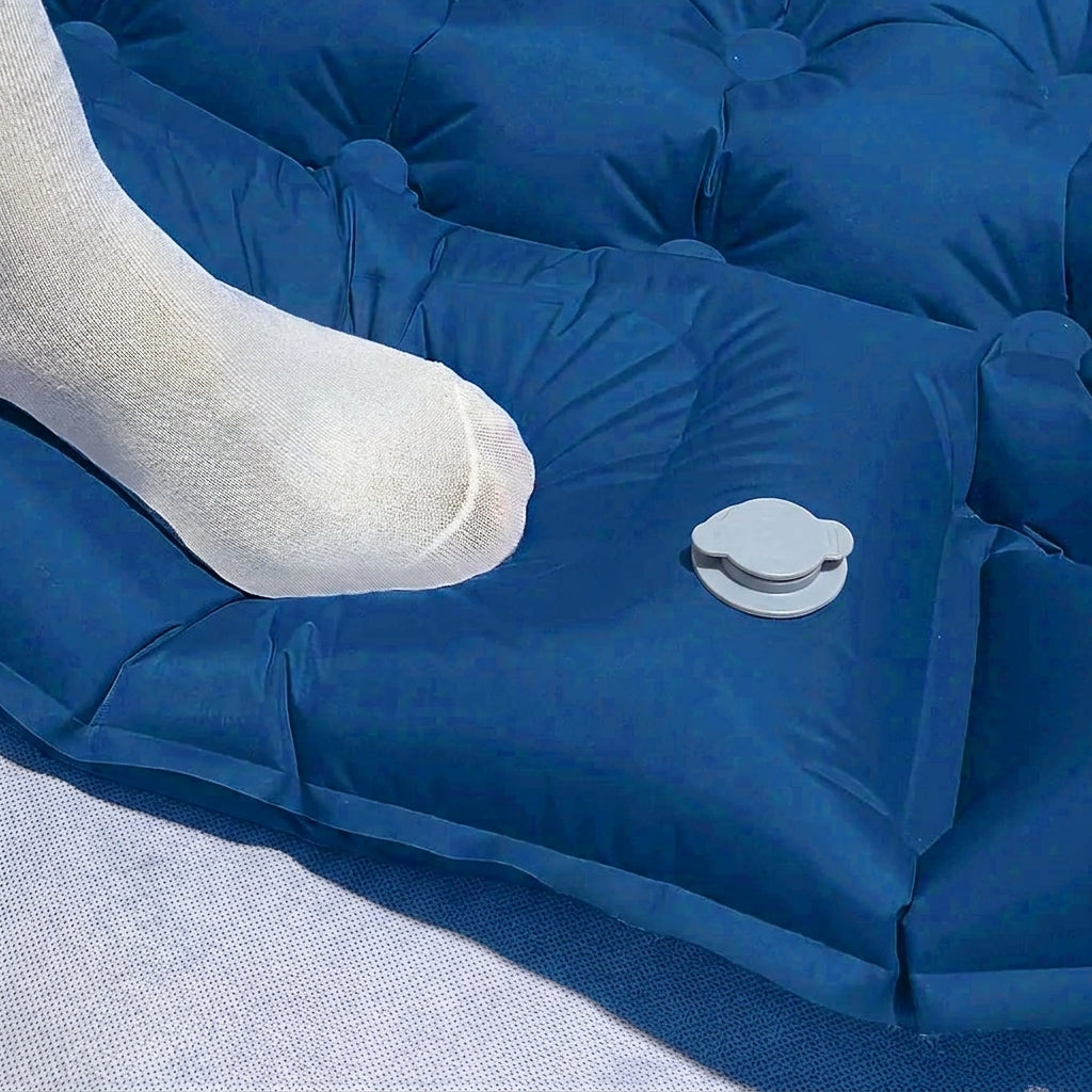 Pied appuyant sur la pompe à pied intégrée du matelas gonflable Belmont-Air